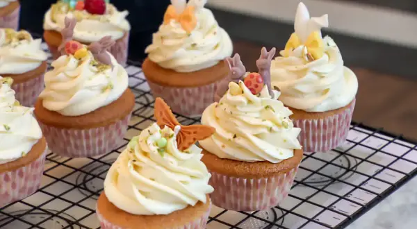 Zarte Vanille Cupcakes mit cremiger Glasur, verziert mit süßen Osterhasen und bunten Eiern. Ein Fest für die Augen und den Gaumen!