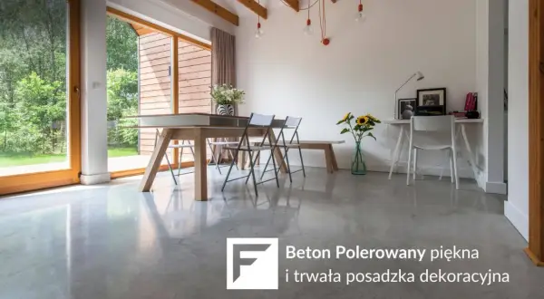 Nowoczesne wnętrze z dużymi oknami i betonem polerowanym na podłodze. W centralnej części stół jadalniany, obok biurko.