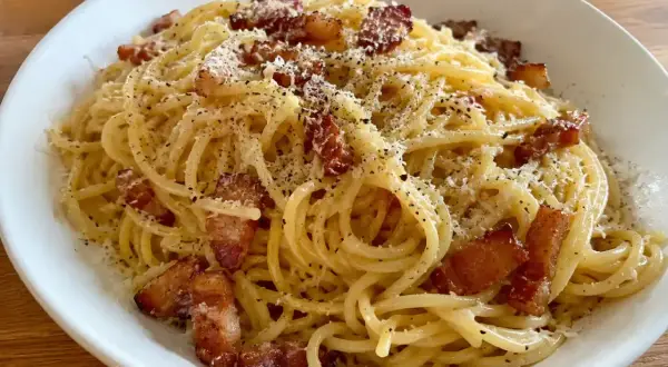 En krämig carbonara med pancetta, toppad med riven ost och svartpeppar. En klassisk italiensk rätt som ser utsökt ut.