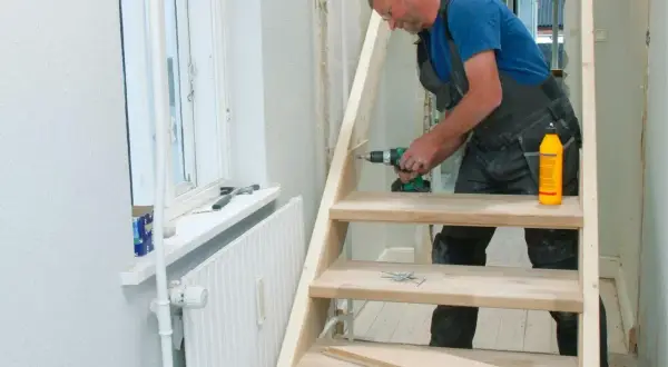 Man bygger trappa inomhus med skruvdragare och trälim.