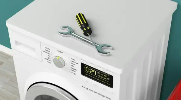 Outil de réparation sur un sèche-linge qui ne sèche plus. Le tournevis et la clé indiquent un problème.