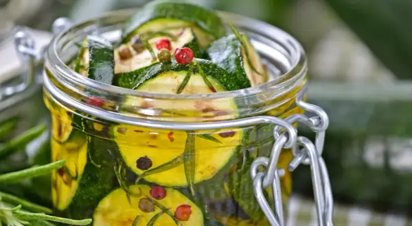 Ein Glas mit eingelegten Zucchini, Kräutern und bunten Pfefferkörnern. Perfekt für den Sommer!