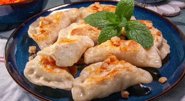 Pyszne pierogi ruskie przepis babci, okraszone skwarkami i udekorowane miętą.