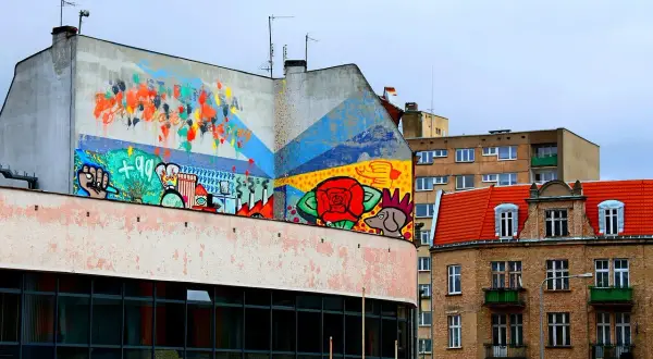 Kolorowy mural na budynku, pełen symboli i abstrakcji, to przykład tego, czym jest postmodernizm w sztuce miejskiej.