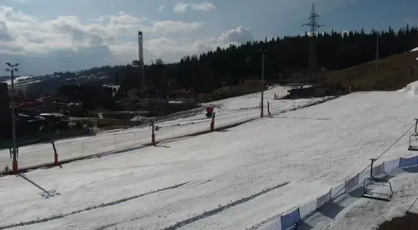 Widok z białka tatrzańska webcam na ośnieżony stok narciarski z wyciągiem krzesełkowym i wieżą w tle.