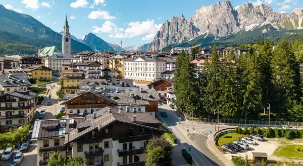 Vue d'un village pittoresque niché au pied des Dolomites en Italie, avec des maisons traditionnelles et une église imposante.