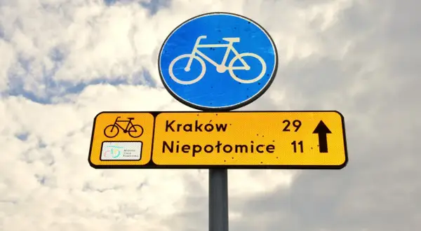 Znak drogowy informuje, że kiedy rowerzysta ma pierwszeństwo, kieruje się na Kraków (29 km) i Niepołomice (11 km).