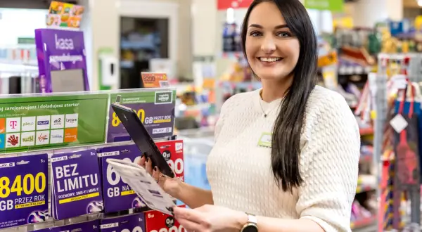 Uśmiechnięta pracownica w sklepie z ofertami telefonii komórkowej. W tle półki z kartami SIM i starterami. Czy to jest właśnie ten model franczyzy, o którym słyszałeś?