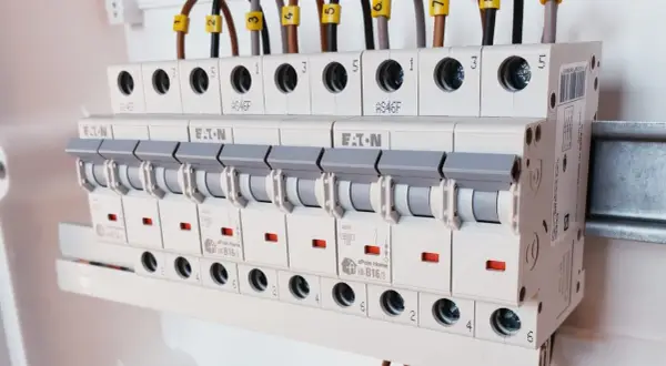 Rzędy bezpieczników w rozdzielnicy elektrycznej, różne rodzaje bezpieczników i ich oznaczenia.