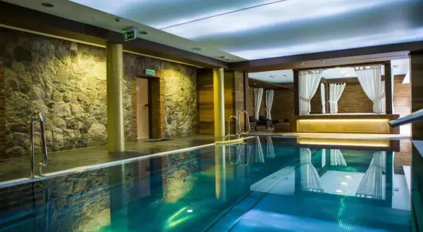 Basen w hotelu Aubrecht Country Spa Resort. Kamienne ściany i zasłonięte baldachimy tworzą atmosferę relaksu, idealną do czytania hotel aubrecht country spa resort opinie.