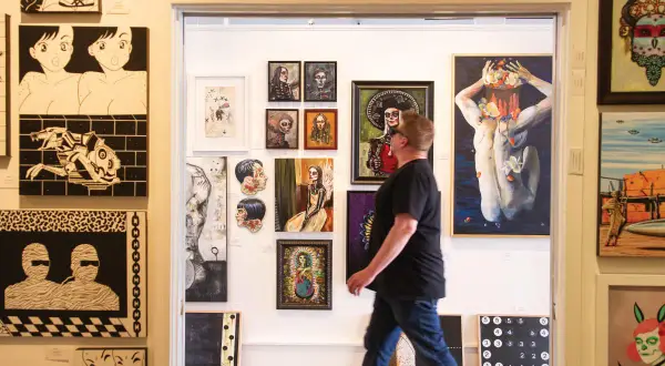 A man walks through a doorway into a vibrant display of art, showcasing diverse styles at Santa Fe art galleries.
