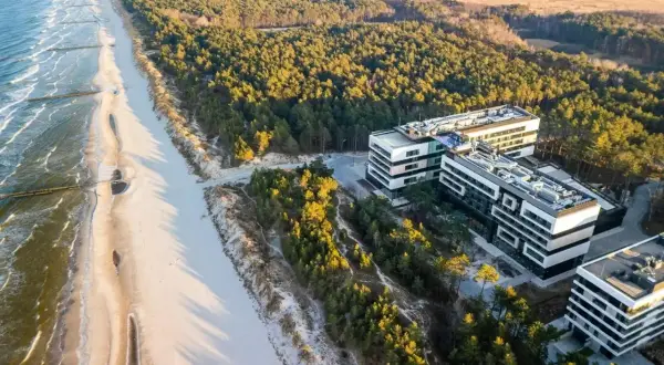 Traumhafter **Polen Urlaub** an der Ostsee: Moderne Hotels neben einem breiten Sandstrand und Kiefernwald.