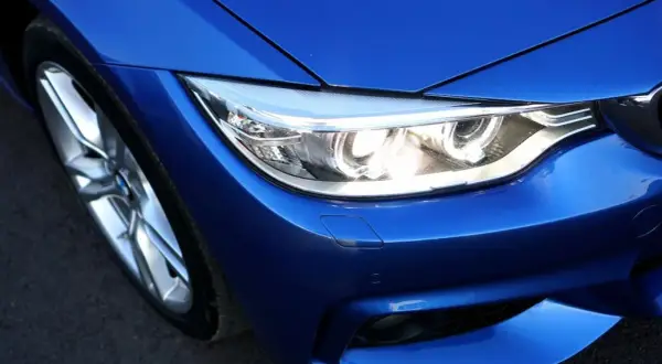 Gros plan sur le phare d'une voiture bleue éclatante, prêt à illuminer la route.