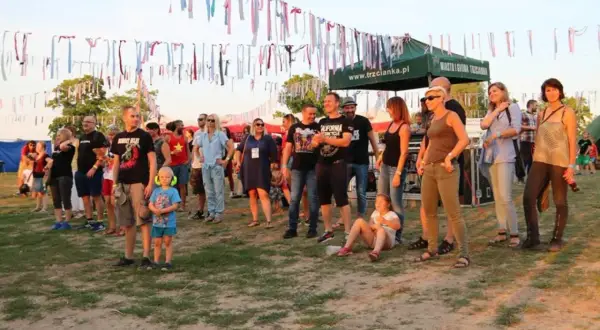 Ludzie na festiwalu trzcianka, w tle kolorowe wstążki i namioty.