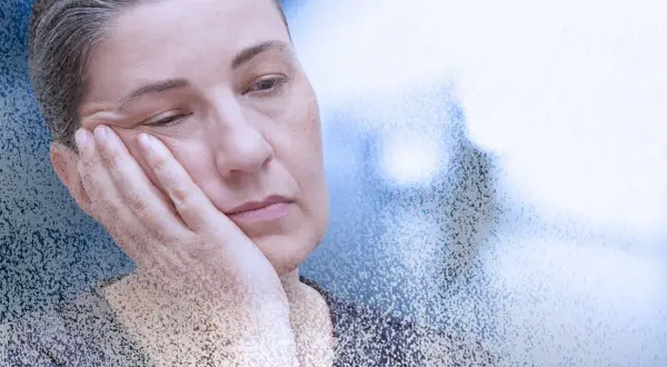 Zmęczona kobieta z dłonią na policzku, symbolizująca mgłę covidową i długotrwałe skutki choroby.