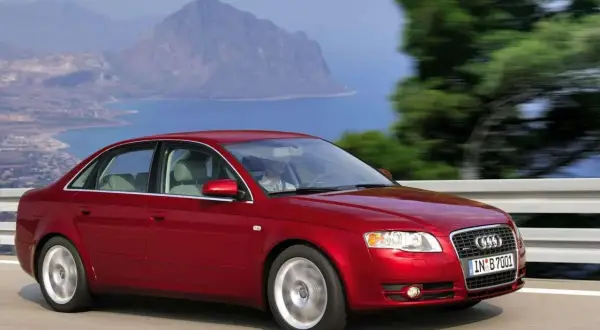 Czerwone Audi 2.0 TDI sunie po drodze z widokiem na morze i góry.