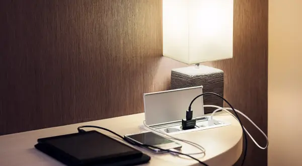 Elegancka ładowarka z gniazdkami i portami USB, idealna do tego, jak ukryć kable. Obok leżą tablet i smartfon.