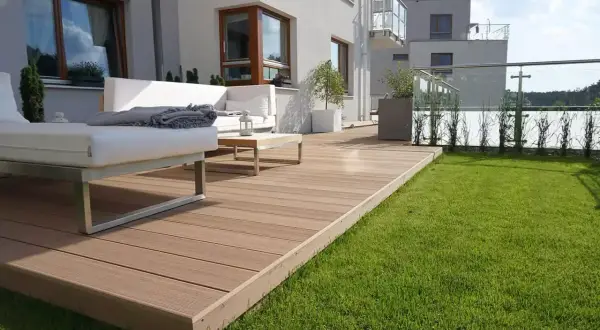 Nowoczesna deska kompozytowa montaż bez legarów tworzy elegancki taras z białymi meblami i zielonym trawnikiem.