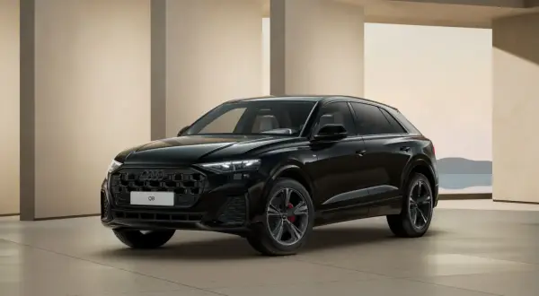 Elegancki, czarny Audi Q8 2025 z czarnym grillem i czerwonymi zaciskami hamulcowymi, zaparkowany przed nowoczesną architekturą.