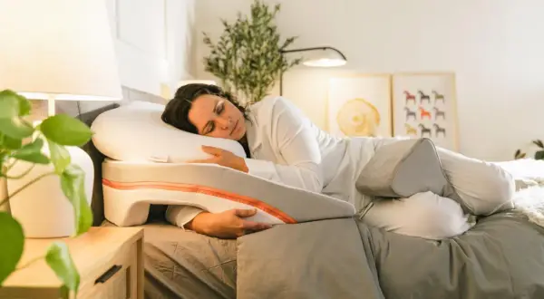 Woman sleeping peacefully on a specialized pillow designed to help with snoring. This pillow offers support for a comfortable sleep position, showing como poner la almohada para no roncar.