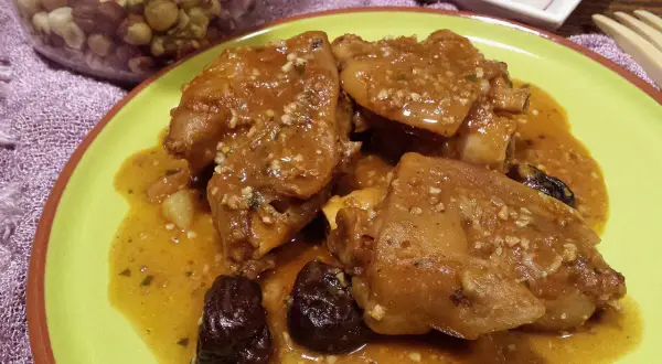 Pies de cerdo a la catalana, un plato tradicional con trozos de cerdo en una salsa dorada, acompañado de ciruelas pasas.