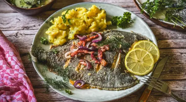 Scholle Finkenwerder Art mit Kartoffelsalat und Gurkensalat, garniert mit Zitrone und Dill.
