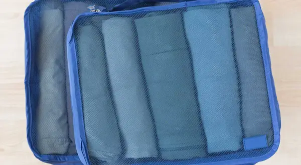Två blå packpåsar med rullade kläder. Ett perfekt **pile material** för organiserad packning.