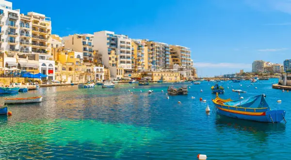 Malta: kolorowe łodzie kołyszą się na turkusowej wodzie, a w tle piętrzą się białe budynki. Idealne miejsce, by poczuć śródziemnomorski klimat i wydać ostatnią malta waluta.