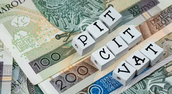 Polskie banknoty z napisami PIT i VAT. Ulga na złe długi może pomóc w rozliczeniu podatków.
