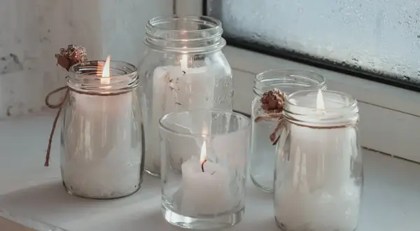 Fünf Windlichter mit Kerzen, die zum Windlicht selber machen inspirieren. Dekoriert mit Zapfen und Juteband.