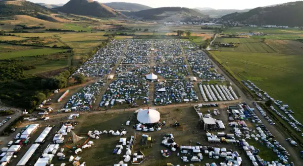 Vasto accampamento di tende e camper per il festival celtico Montelago, immerso in un paesaggio collinare verdeggiante.