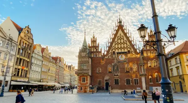 Der Marktplatz in Breslau mit dem historischen Rathaus und bunten Häusern. Ein sonniger Tag am Bahnhof Breslau.