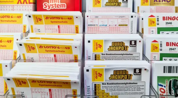 Stojaki z kuponami lotto, w tym Eurojackpot, Lotto 6 aus 49 i Keno.