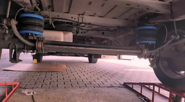 Podwozie pojazdu z zamontowanym zawieszeniem hydropneumatycznym. Dwa niebieskie miechy pneumatyczne są widoczne po obu stronach tylnej osi.
