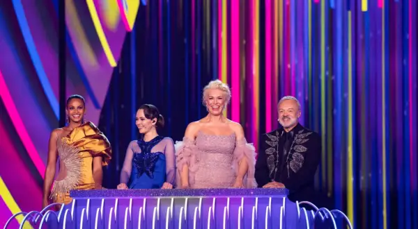 Cztery osoby na scenie z kolorowym tłem. Jedna z nich, w złotej sukni, może reprezentować Polskę na Eurowizji.