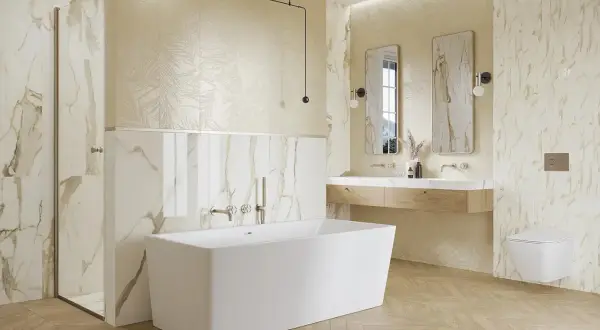 Elegancka łazienka z wanną wolnostojącą, prysznicem i podwójną umywalką. Dominują płytki imitujące marmur z subtelnymi złotymi żyłkami.