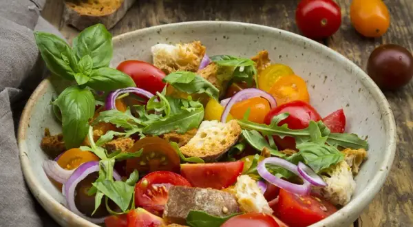 Bunter Salat mit Tomaten, Brotstücken und Rucola, verfeinert mit einem Hauch Balsamico Dressing.
