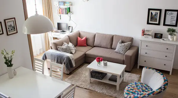 Przytulny salon z narożnikiem, stołem i biurkiem. Układ mieszkań w bloku z wielkiej płyty zaaranżowany na nowo.