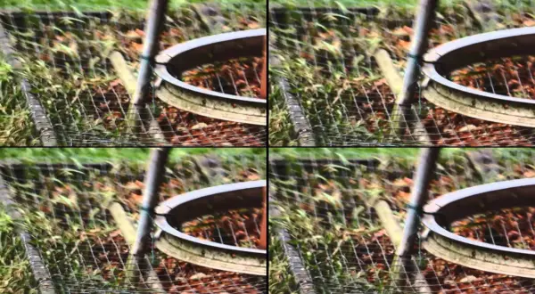 Zniekształcony obraz z efektem rolling shutter, ukazujący fragment ogrodzenia i ziemi.