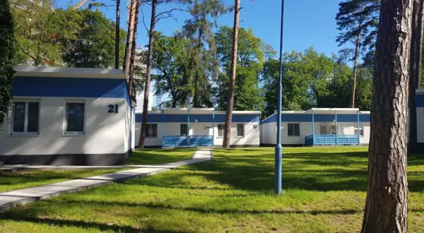 Urocze domki letniskowe w Międzyzdrojach, otoczone zielenią, zapraszają na wypoczynek. Numer 21 widoczny na jednym z budynków.
