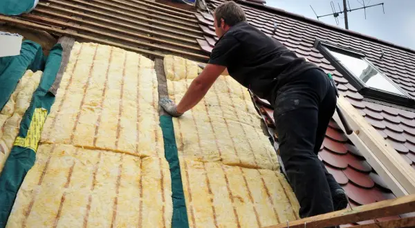Dachdecker verlegt Dämmung. Energetische Sanierung Pflicht: So wird das Haus winterfest und spart Heizkosten.