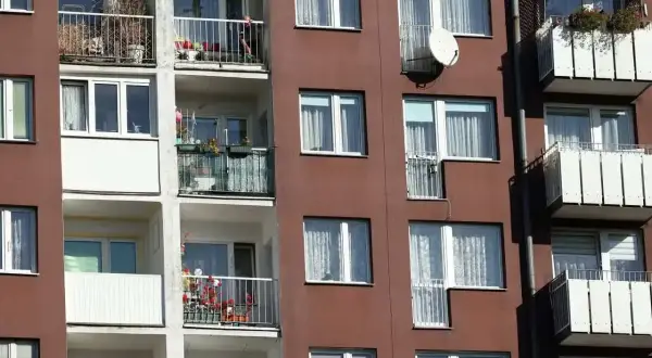 Blok mieszkalny z balkonami, na których widać rośliny i antenę satelitarną. Czy mieszkanie TBS można wykupić?