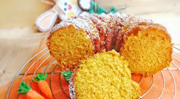 Torta di carote Bimby soffice e profumata, decorata con zucchero a velo e carotine decorative.