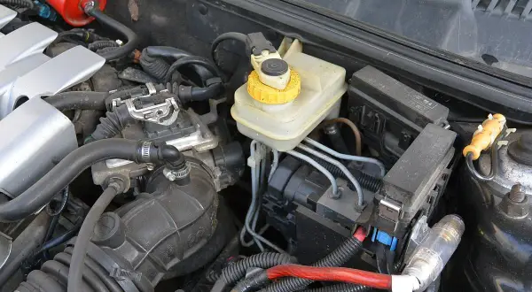 Silnik samochodu z widocznym zbiorniczkiem płynu hamulcowego i elementami układu elektrycznego. Uszkodzony zawór zwrotny serwa objawy mogą być trudne do zdiagnozowania.