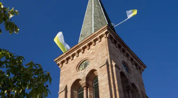 Kirchturm mit Fahnen im Wind, ein Zeichen, dass die Kirchweih gefeiert wird.