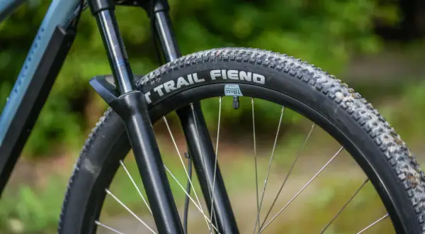 Opona rowerowa "Trail Fiend" z widocznym bieżnikiem, zwijana, gotowa na terenowe wyzwania.