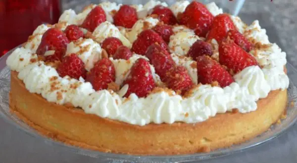 Délicieuse tarte aux fraises chantilly, garnie de fruits rouges frais et de crème onctueuse, saupoudrée de miettes croustillantes.