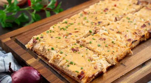 Saftiger Zwiebelkuchen vom Blech, goldbraun gebacken und mit Schnittlauch bestreut. Ein Genuss für jeden Anlass!