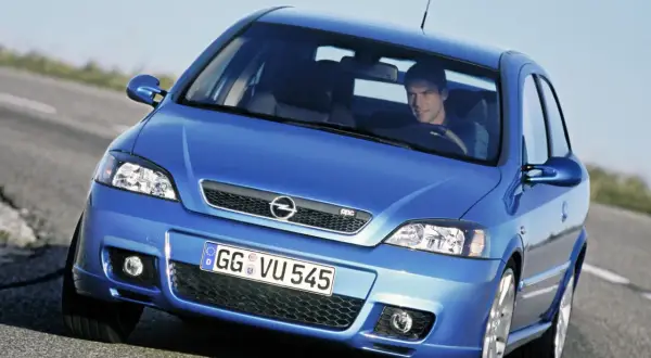 Niebieski Opel Astra G CC z kierowcą na drodze.