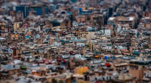 A dense cityscape rendered with tilt shift photography, making the buildings appear like miniature models.